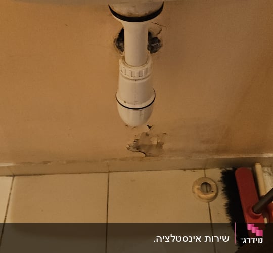 כיור עם צינור ניקוז וקיר פגום